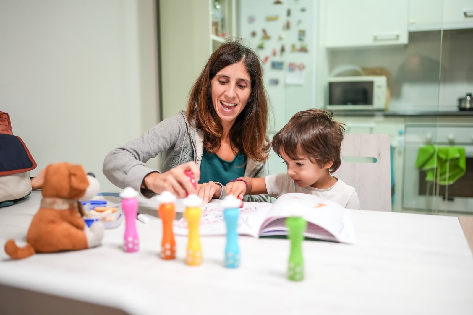 Mother and young son doing a hands-on activity together at the kitchen table