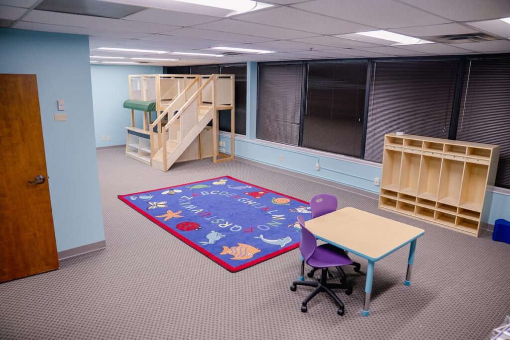 Activity room with a play loft, rug and learning table at the Step It Up ABA Northlake center