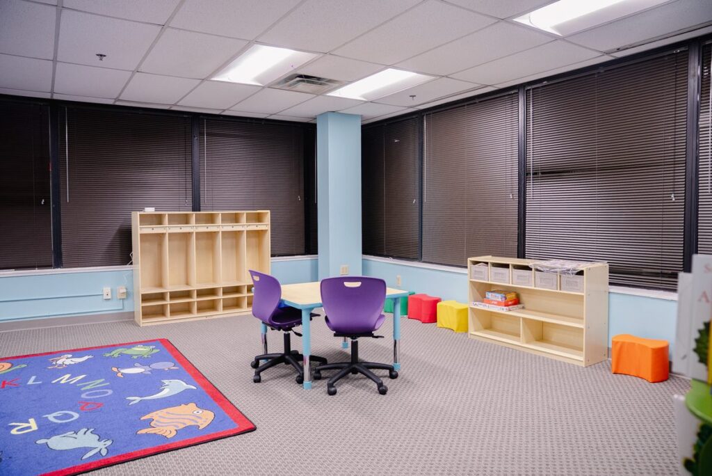 Play area with an alphabet rug, cubbies and a table at the Step It Up ABA Northlake center