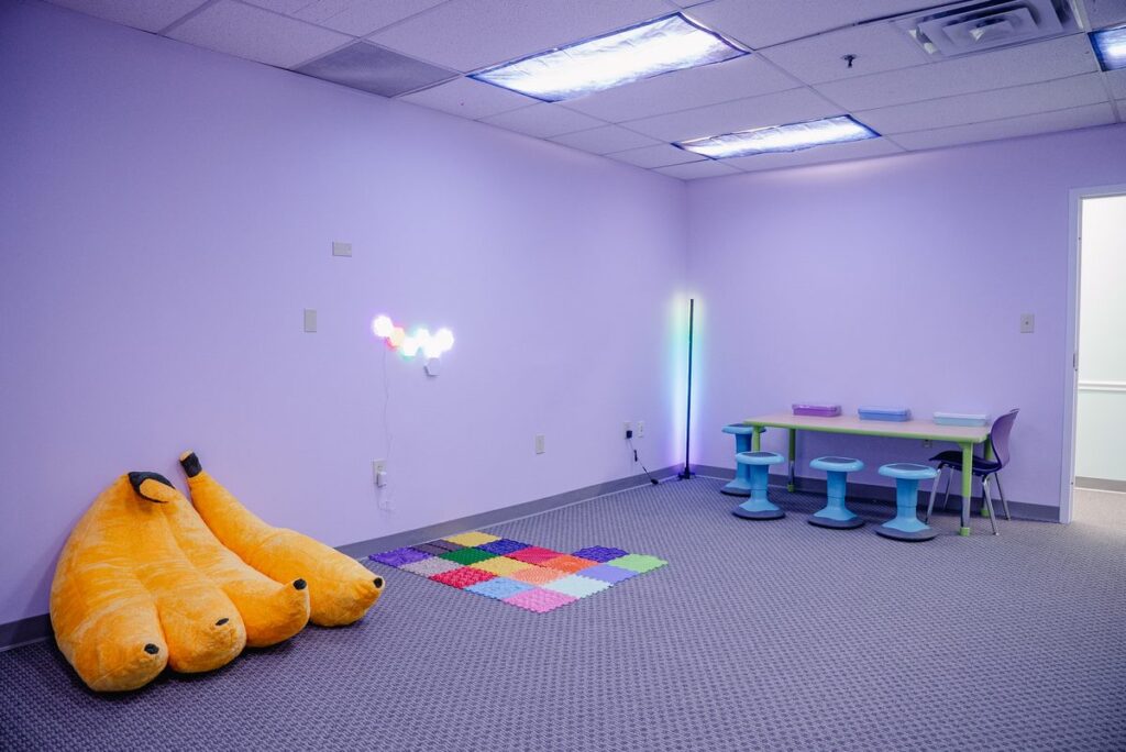 Sensory room with soft seating and small tables at the Step It Up ABA Northlake center