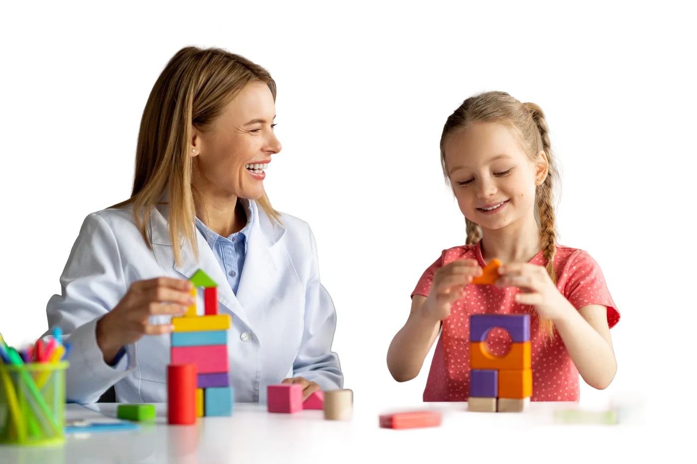 Smiling therapist building with colorful blocks alongside a young girl