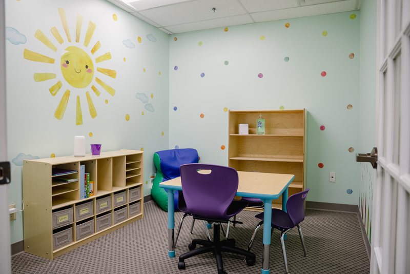 Step It Up ABA therapy room with a sun mural and learning shelves